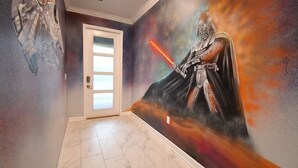 A hallway with a mural of a character holding a lightsaber, a door, and a marble floor. - 5BR/5BA Game/Pool Villa 9 Miles to Disney (Kissimmee)