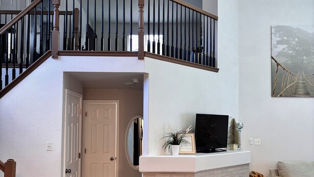 Uma casa de dois andares com escada, lareira, televisão e um quadro na parede.