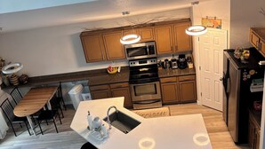 Cozinha moderna com ilha central, eletrodomésticos embutidos e iluminação pendente.