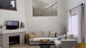 Uma sala de estar moderna com lareira, sofá, mesa de centro e poltronas amarelas.