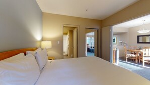 Ett hotellrum med en stor säng, en sänglampa, ett badrum som syns genom en öppen dörr och en matplats med stolar och ett bord.
