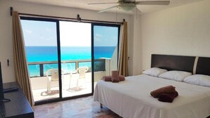Ein Schlafzimmer mit Bett, Deckenventilator und Meerblick durch eine Schiebetür.