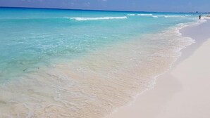 Ein Strand mit klarem türkisblauem Wasser und einem sandigen Ufer.