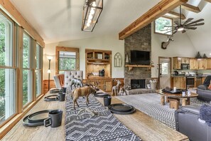 A spacious living room with a fireplace, large windows, and a dining area with a long table.
