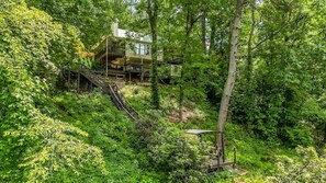 A multi-story building surrounded by dense forest, with a staircase leading to the upper levels.