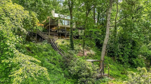 A multi-story building surrounded by dense forest, with a staircase leading to the upper levels.