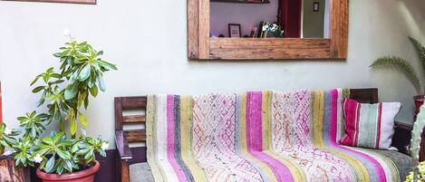 Un salón acogedor con un sofá, un espejo grande y una planta en maceta.