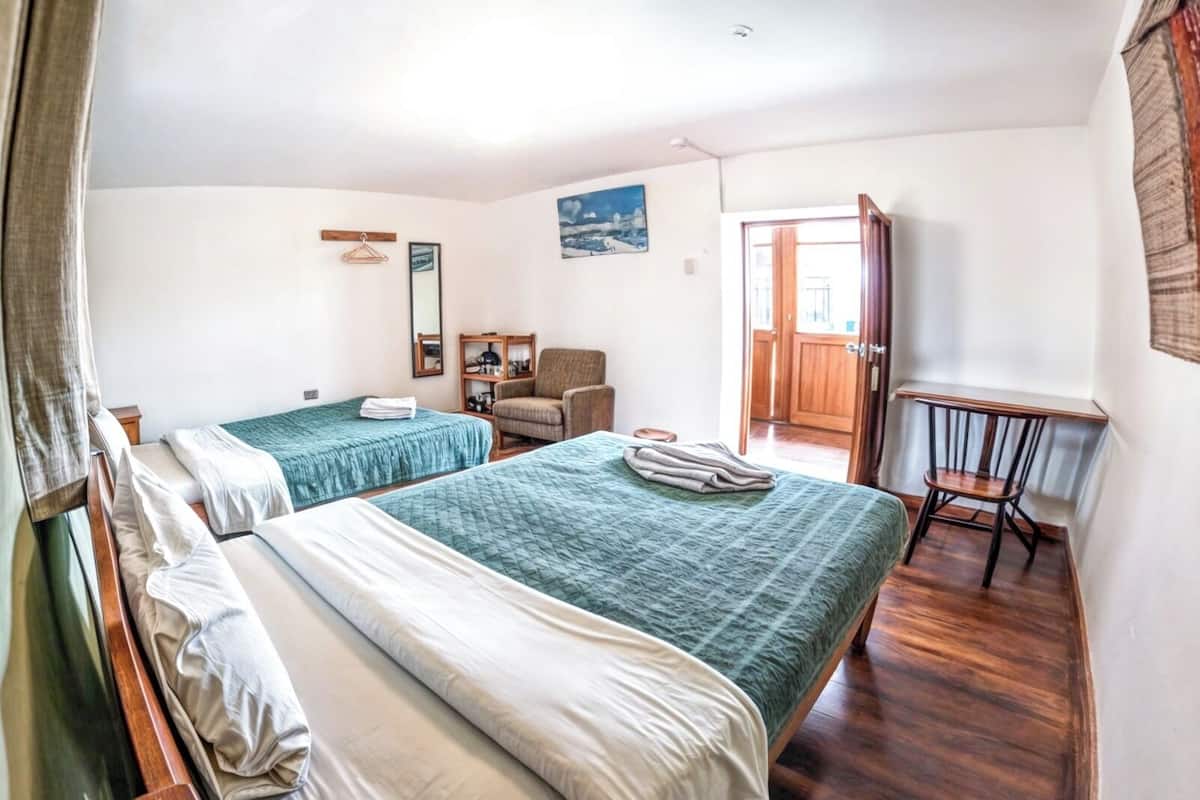 A room with two single beds, a wooden desk, a chair, and a small table.