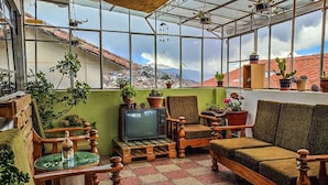 Ein Wintergarten mit Holzzmöbeln, Topfpflanzen und einem Fernseher.