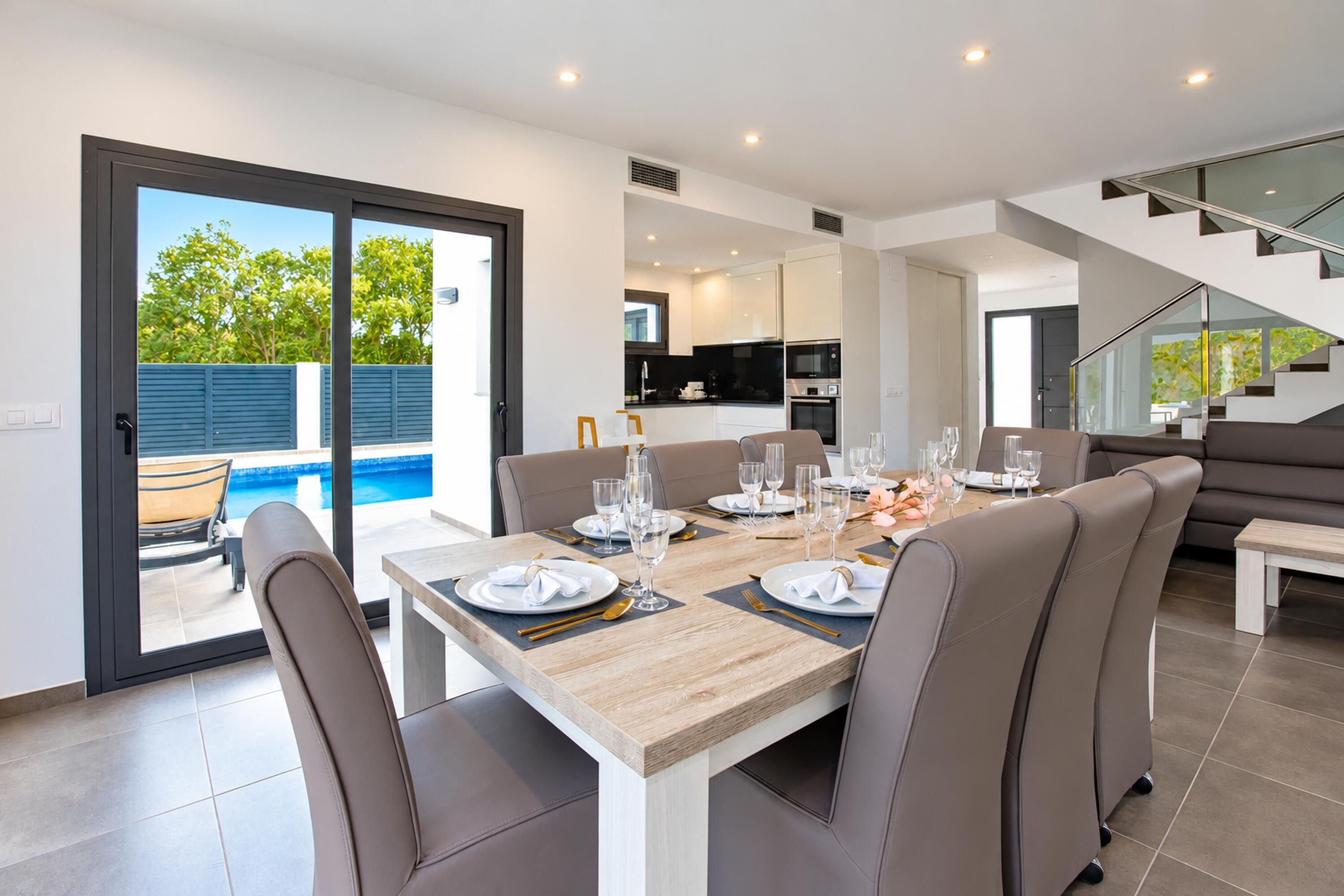 A modern dining area with a wooden table set for six, surrounded by leather chairs.