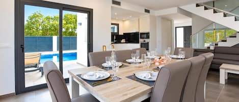 A modern dining area with a wooden table set for six, surrounded by leather chairs.