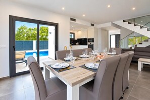 A modern dining area with a wooden table set for six, surrounded by leather chairs.