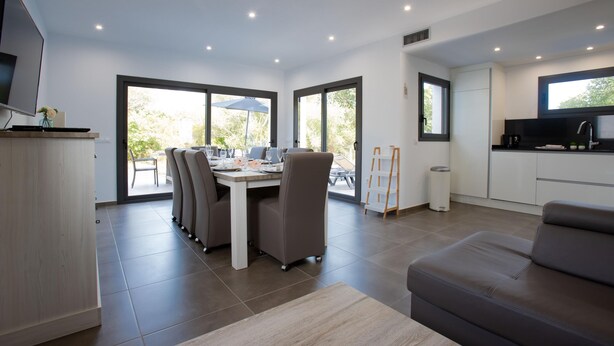 A modern kitchen with a dining area, large windows, and a flat-screen TV. - Villa for rent in Mas Busca, Roses, Costa Brava: Spacious villa with private pool, ideal for families, 3 km from Roses beach. (Roses)