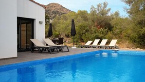 A swimming pool with lounge chairs and umbrellas, surrounded by greenery and a mountain in the background. - Villa for rent in Mas Busca, Roses, Costa Brava: Spacious villa with private pool, ideal for families, 3 km from Roses beach. (Roses)