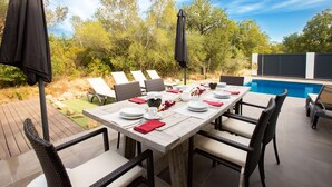 An outdoor dining area with a pool, wicker chairs, and umbrellas. - Villa for rent in Mas Busca, Roses, Costa Brava: Spacious villa with private pool, ideal for families, 3 km from Roses beach. (Roses)