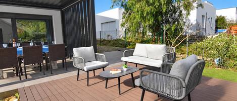 An outdoor patio with wicker furniture, a round table, and a view of a modern building.