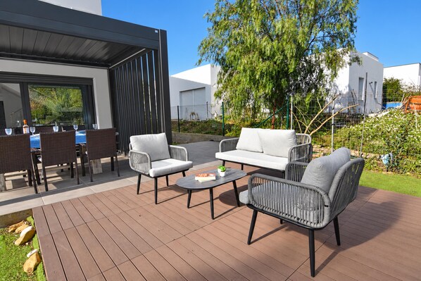 An outdoor patio with wicker furniture, a round table, and a view of a modern building.