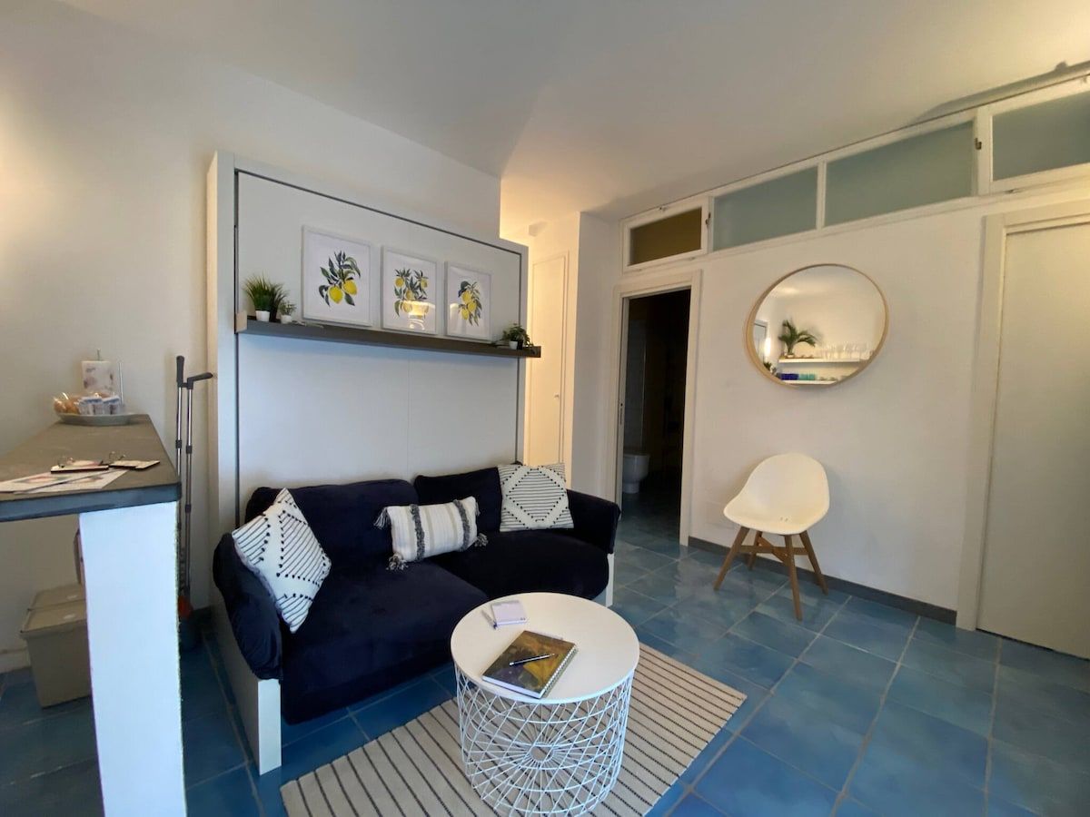 A modern living room with a dark blue sofa, a white coffee table, and a round mirror on the wall.