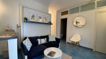 A modern living room with a dark blue sofa, a white coffee table, and a round mirror on the wall.