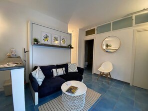 A modern living room with a dark blue sofa, a white coffee table, and a round mirror on the wall. - Fetta di Limone Apartment with Ac and Patio (Monterosso al Mare)