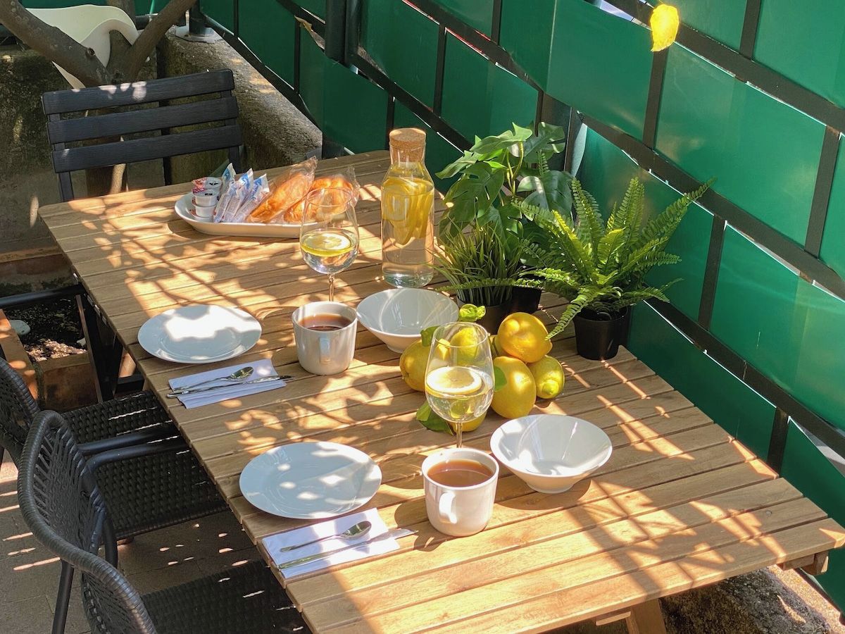 Mesa de comedor al aire libre con platos, recipientes, una botella y limones.