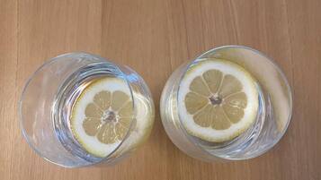 Two glasses of water with lemon slices on a wooden surface.