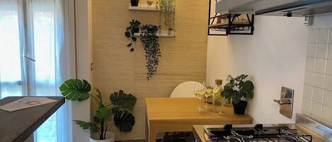 Una cocina con una mesa de madera, estufa a gas y plantas en macetas.