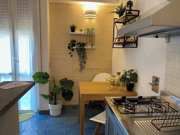 Una cocina con una mesa de madera, estufa a gas y plantas en macetas.