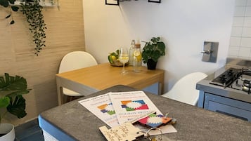 Ett kök med en bänkskiva i granit, ett matbord, stolar, en krukväxt och en hylla med dekorativa föremål.