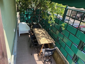 Un patio al aire libre con una mesa y sillas de madera, rodeado por una valla verde.