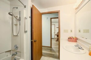 A bathroom with a shower, sink, and mirror.