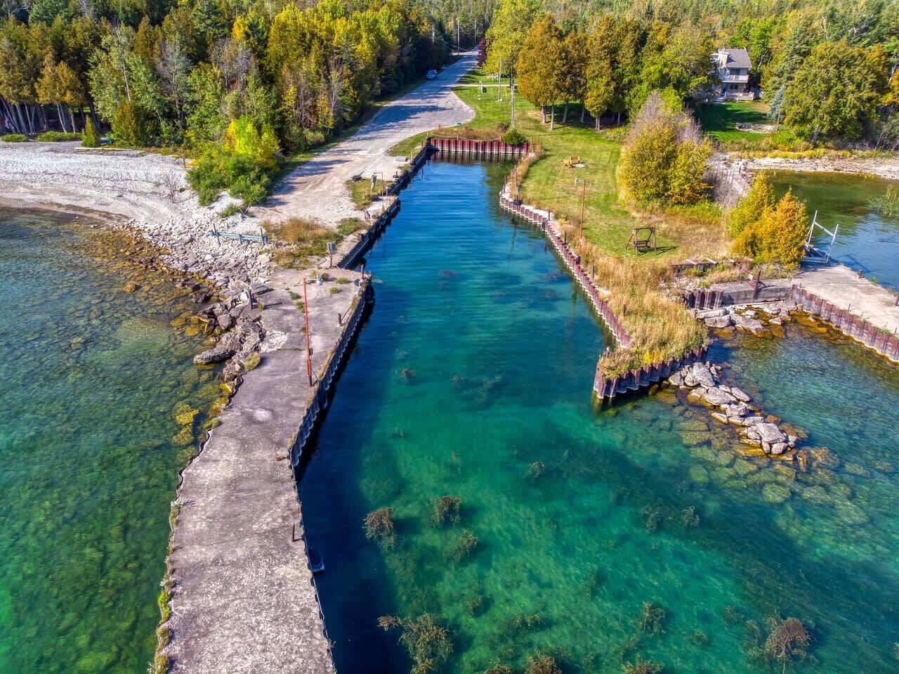 Kirkasvetinen joki, jonka ympärillä on puita ja jonka lähellä sijaitsee talo.