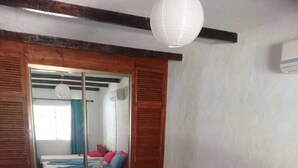 Une chambre à coucher comprenant un lit, une armoire, un miroir et un luminaire suspendu.