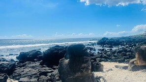 A rocky coastal landscape with large boulders and a clear view of the ocean.