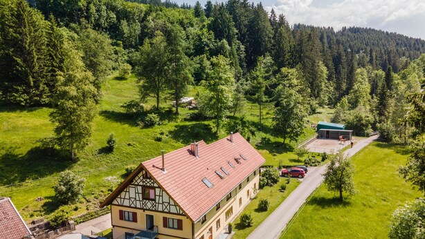 A two-story building with a red roof, a balcony, and a fenced patio area. - Apartment "Balzerberg" with Garden & Wi-Fi (Weiler-Simmerberg)