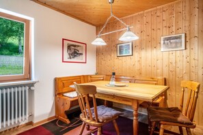 Une pièce aux murs lambrés, avec une table, des chaises, un radiateur et des tableaux encadrés.