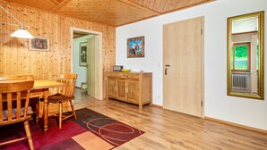 A wooden-paneled room with a dining table, chairs, a cabinet, and a door. - Apartment "Balzerberg" with Garden & Wi-Fi (Weiler-Simmerberg)