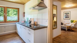 A modern kitchen with a built-in stove, a window, and a dining area with a chair and table.