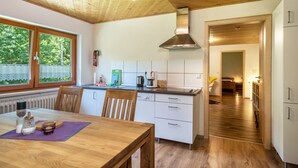 A modern kitchen with wooden cabinets, a stainless steel range hood, and a window with a view of greenery.