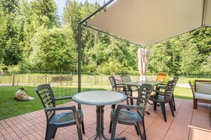 An outdoor patio with a round table and chairs, surrounded by a pergola with a canopy.
