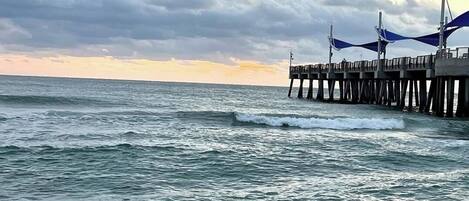 Une jetée qui s’avance dans l’océan, avec des vagues qui se brisent sur le rivage.