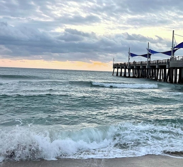 Un muelle que se adentra en el océano, con olas rompiendo en la orilla.