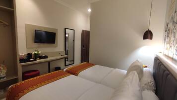 Habitación de hotel con dos camas, televisión, espejo, escritorio y armario.