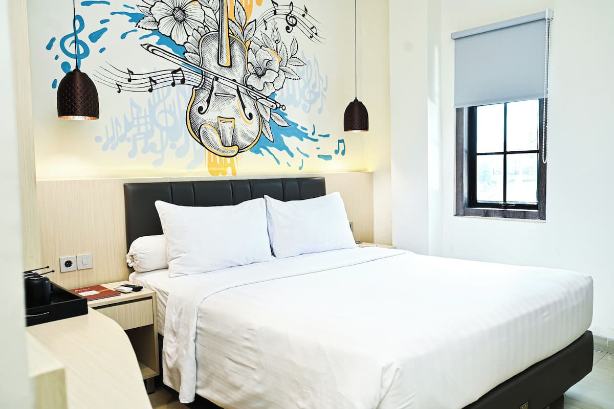 A modern hotel room with a large bed, a nightstand, a desk, and a window with a view.