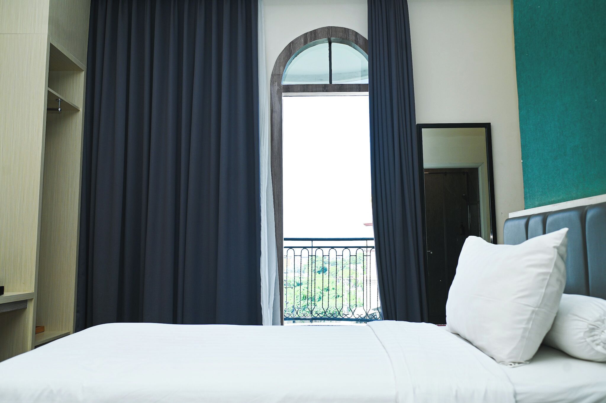 Une chambre d’hôtel avec un lit, une armoire, une fenêtre avec des rideaux et une vue sur la verdure.