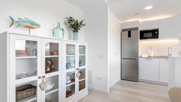 Una cocina moderna con armarios blancos, un refrigerador de acero inoxidable y un microondas.