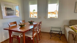 A dining area with a wooden table and chairs, a glass coffee table, and a sofa.