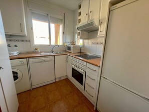 A compact kitchen with a washing machine, dishwasher, microwave, stove, and a refrigerator.