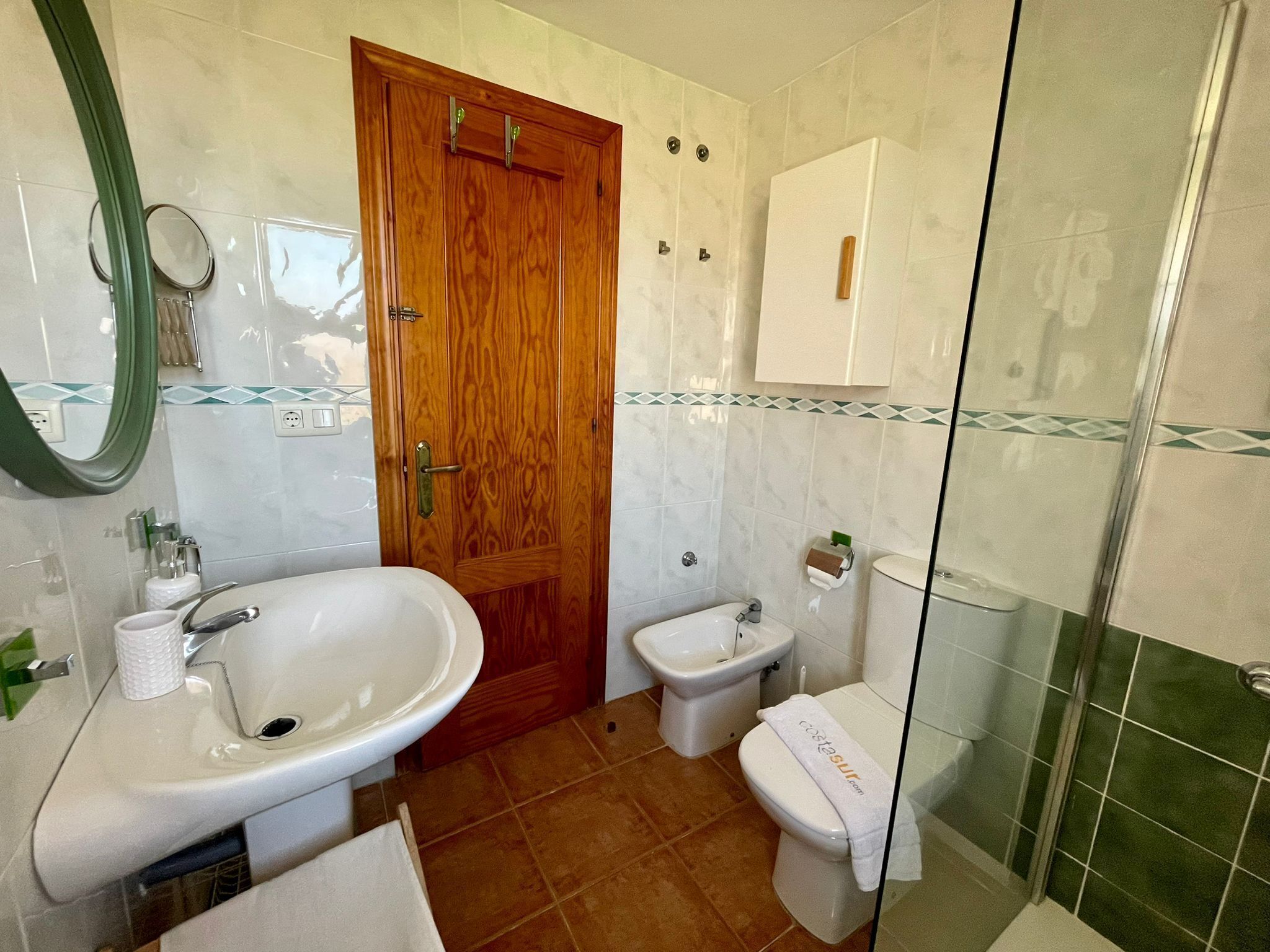 Ein Badezimmer mit Holztür, Waschbecken, integriertem Bidet und Toilette.