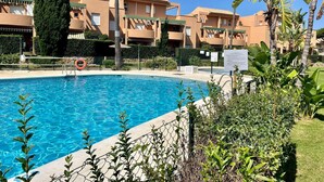 A swimming pool with a clear blue water surface, surrounded by a chain-link fence.